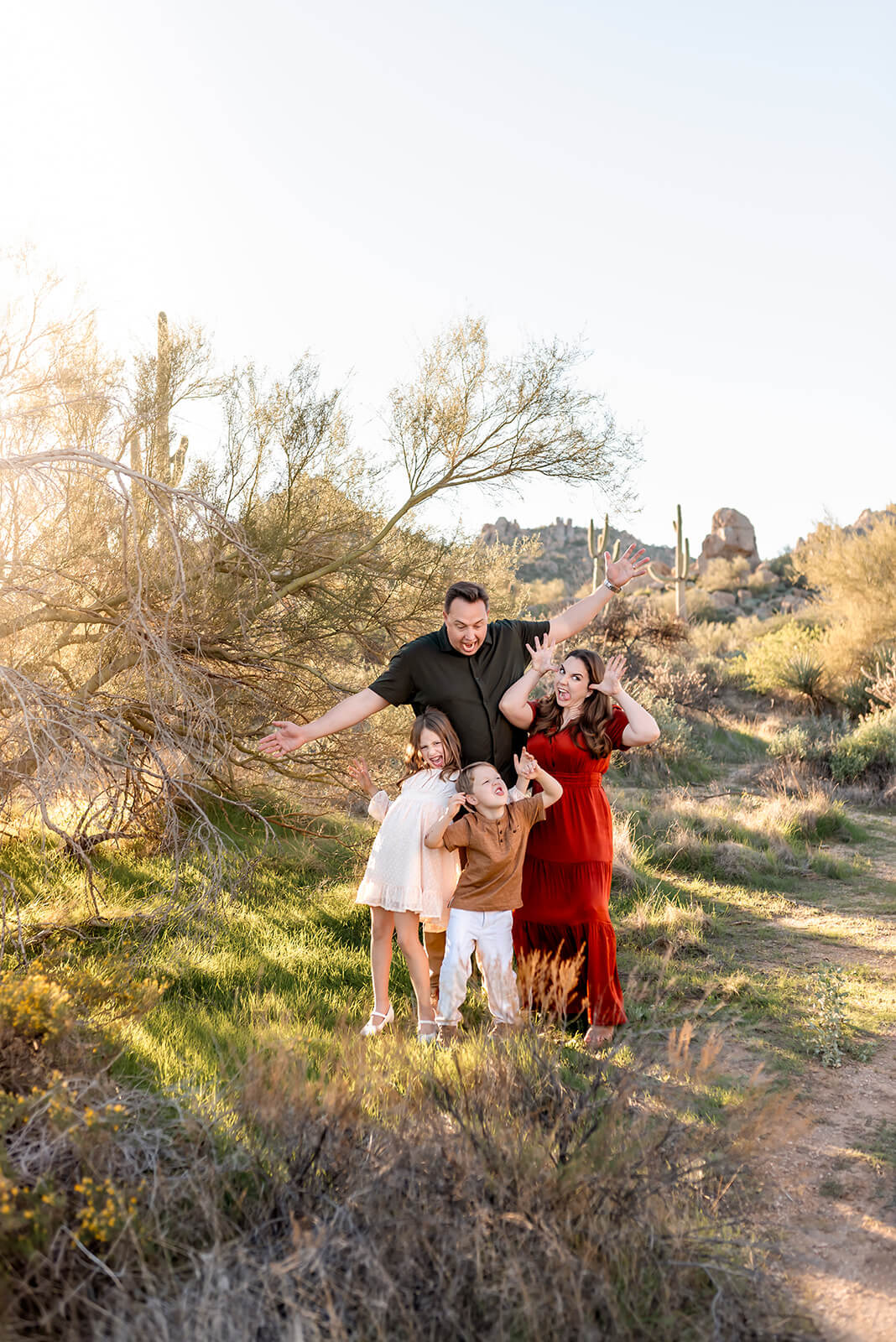 Family of four make goofy faces while posing in great outfits for desert family photos