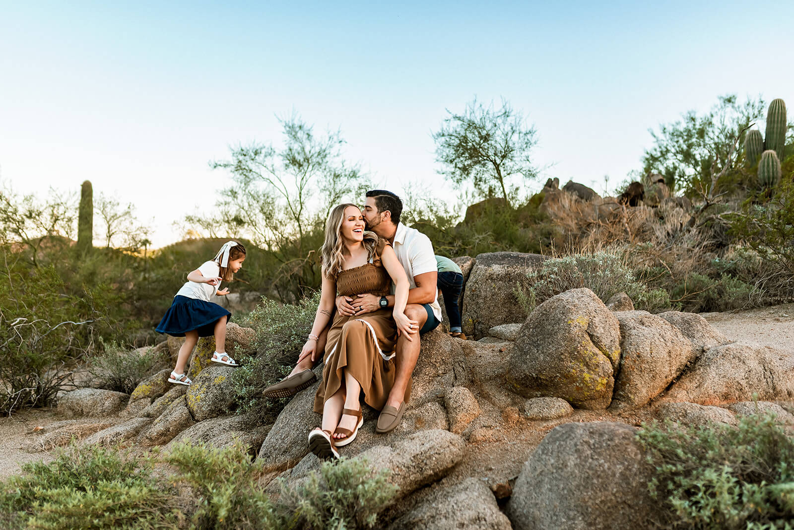 Mom and dad sit on boulders while boy and girl play around them