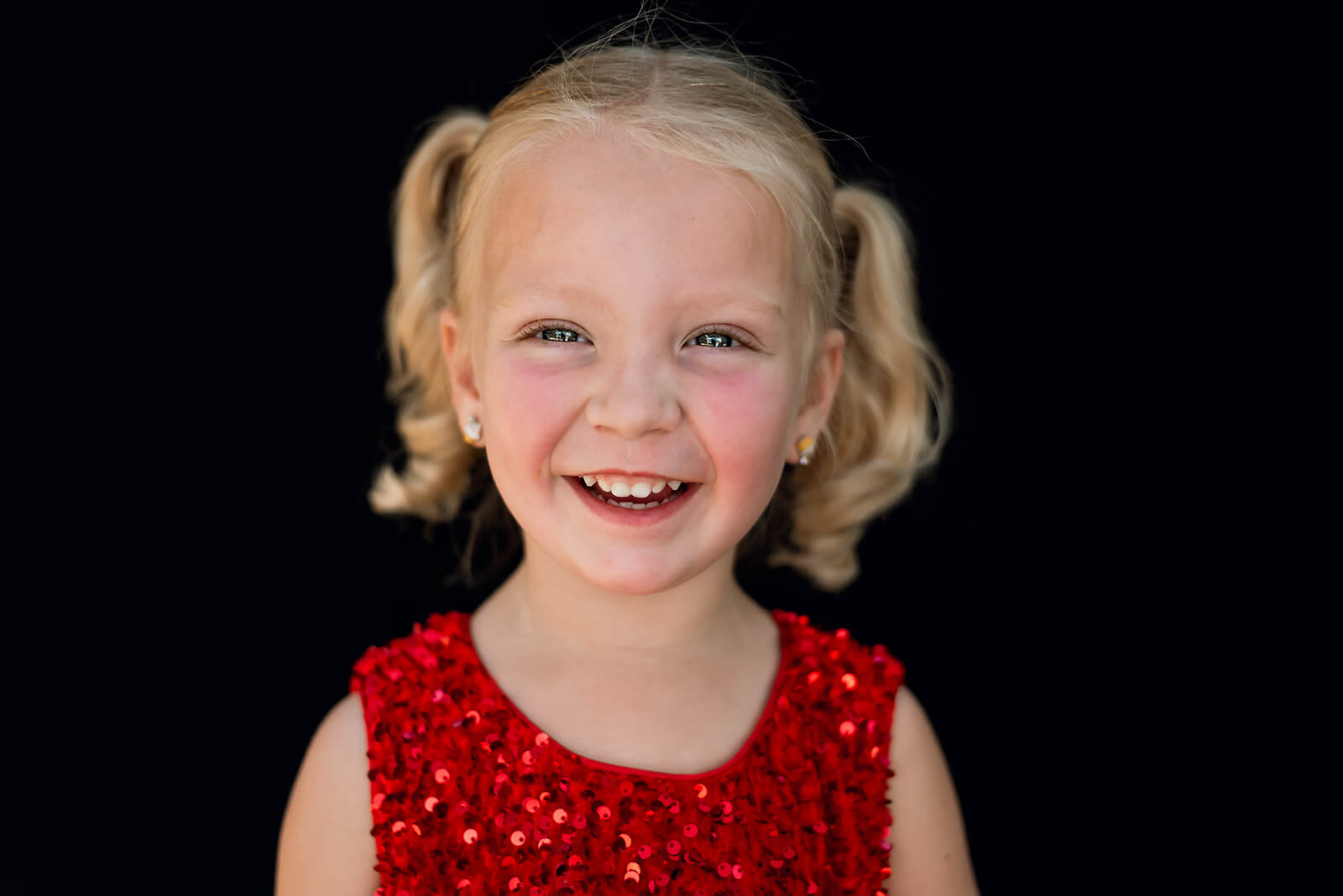 Little girl wearing a red dress smiles and laughs during a fine art school portrait photo session