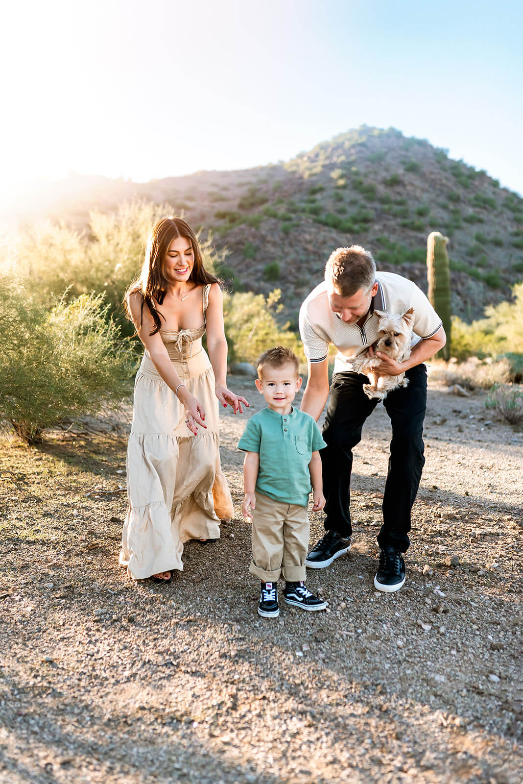 Mom and dad chase after toddler boy in golden hour desert photography photo session.