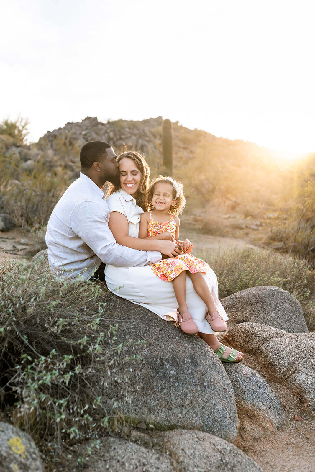 Family of three sit on a rock during a spring desert family photo session
