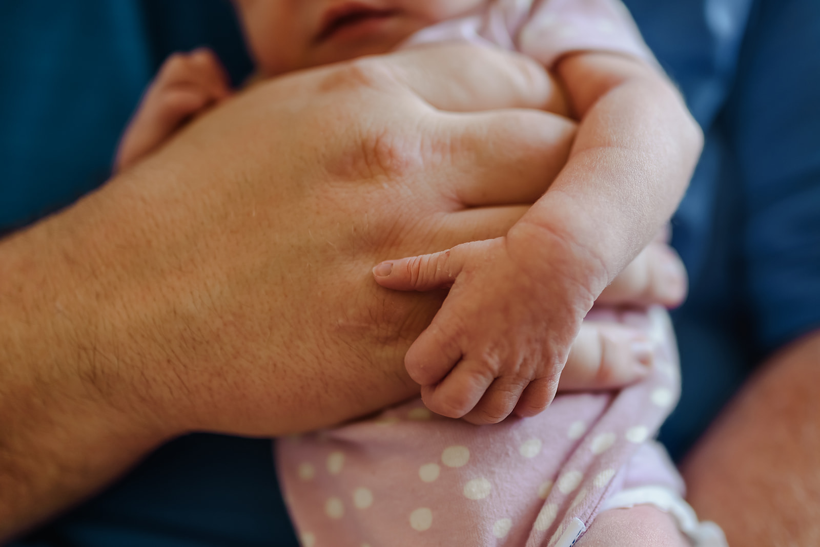 Details of a newborn babies hand with her dad's hand.
