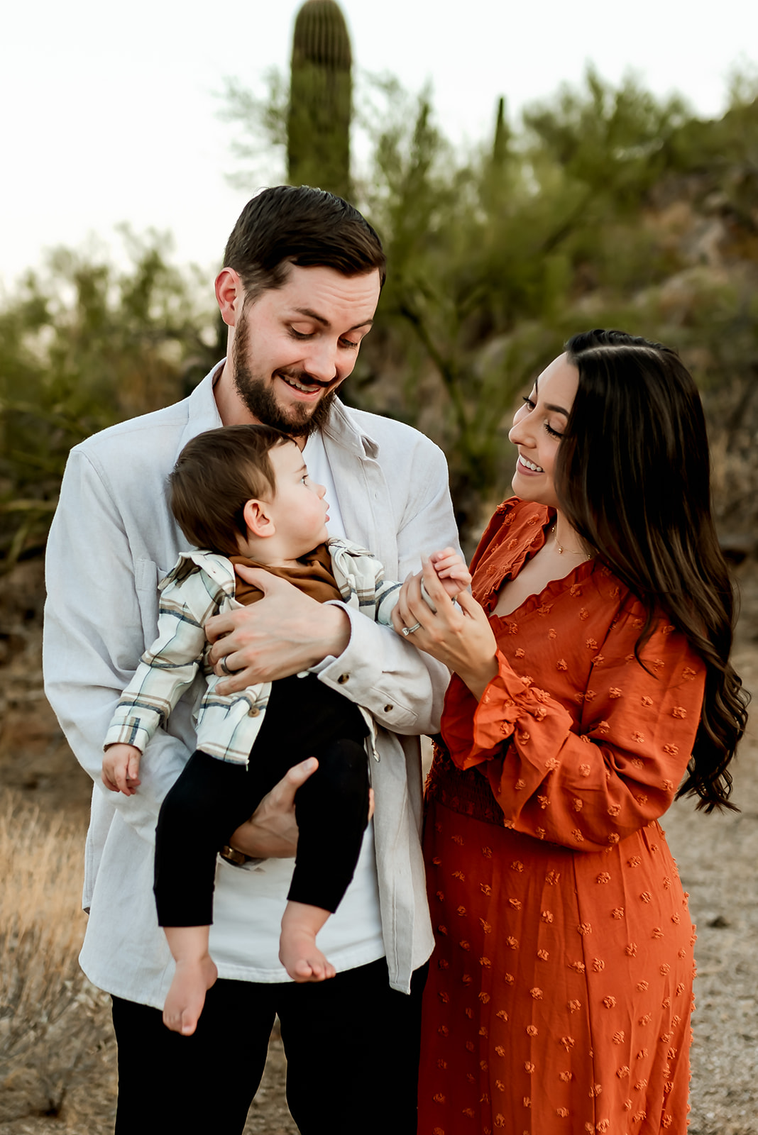 Mom engages with baby who is being held by his dad in a family photo session