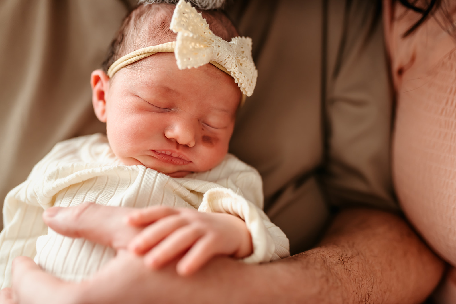 Newborn girl is held by her dad sleeping.
