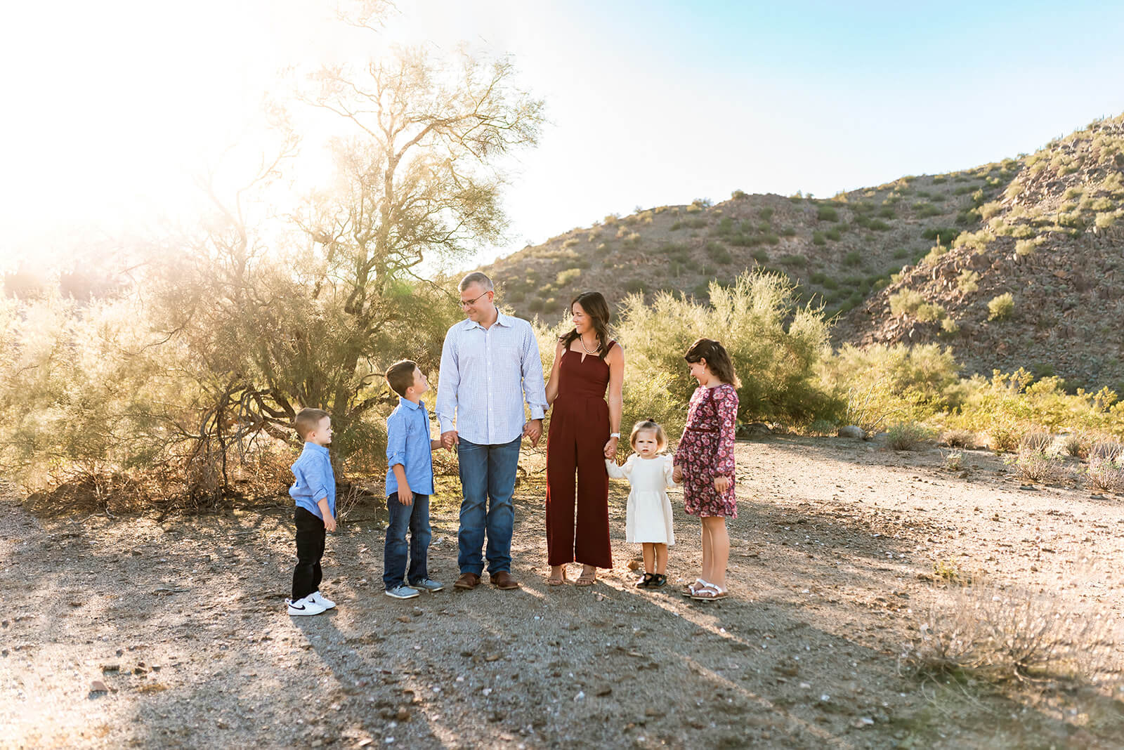Family of 5 hold hands and look at each other during a family photo session.