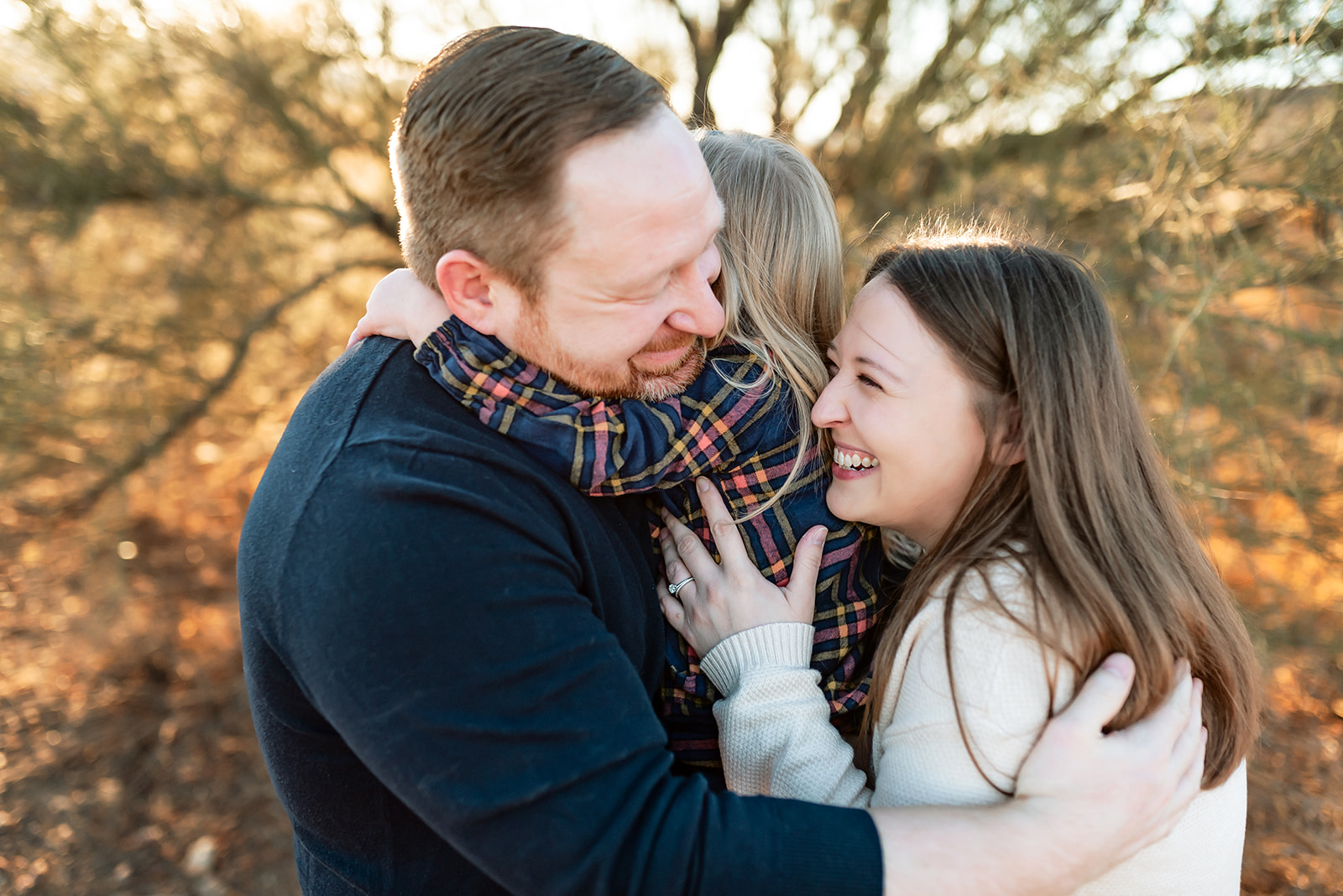 Family of three embrace during Phoenix family photos and a precious moment is frozen in time.