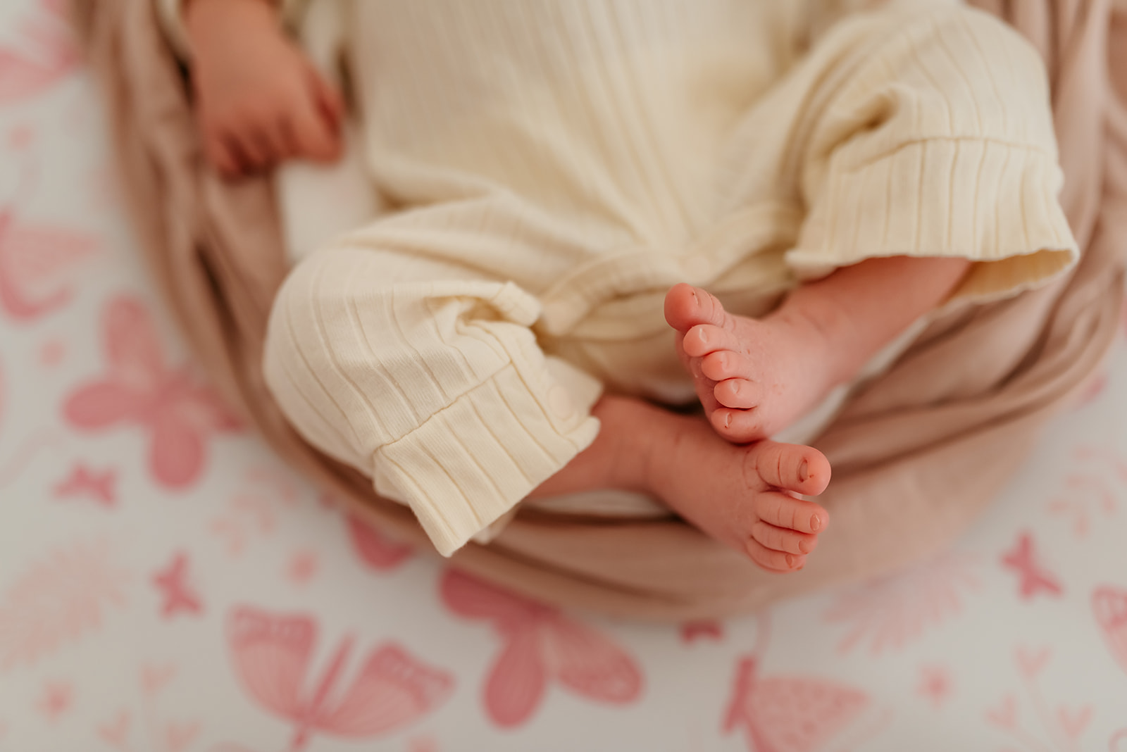 Details of a newborn baby's toes against a butterfly sheet.