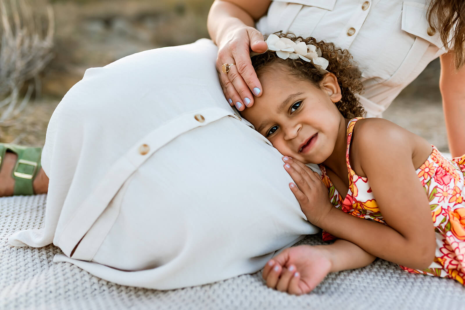 Little girl lays on her mother's lap while mom strokes her forehead during a Phoenix family photo shoot.
